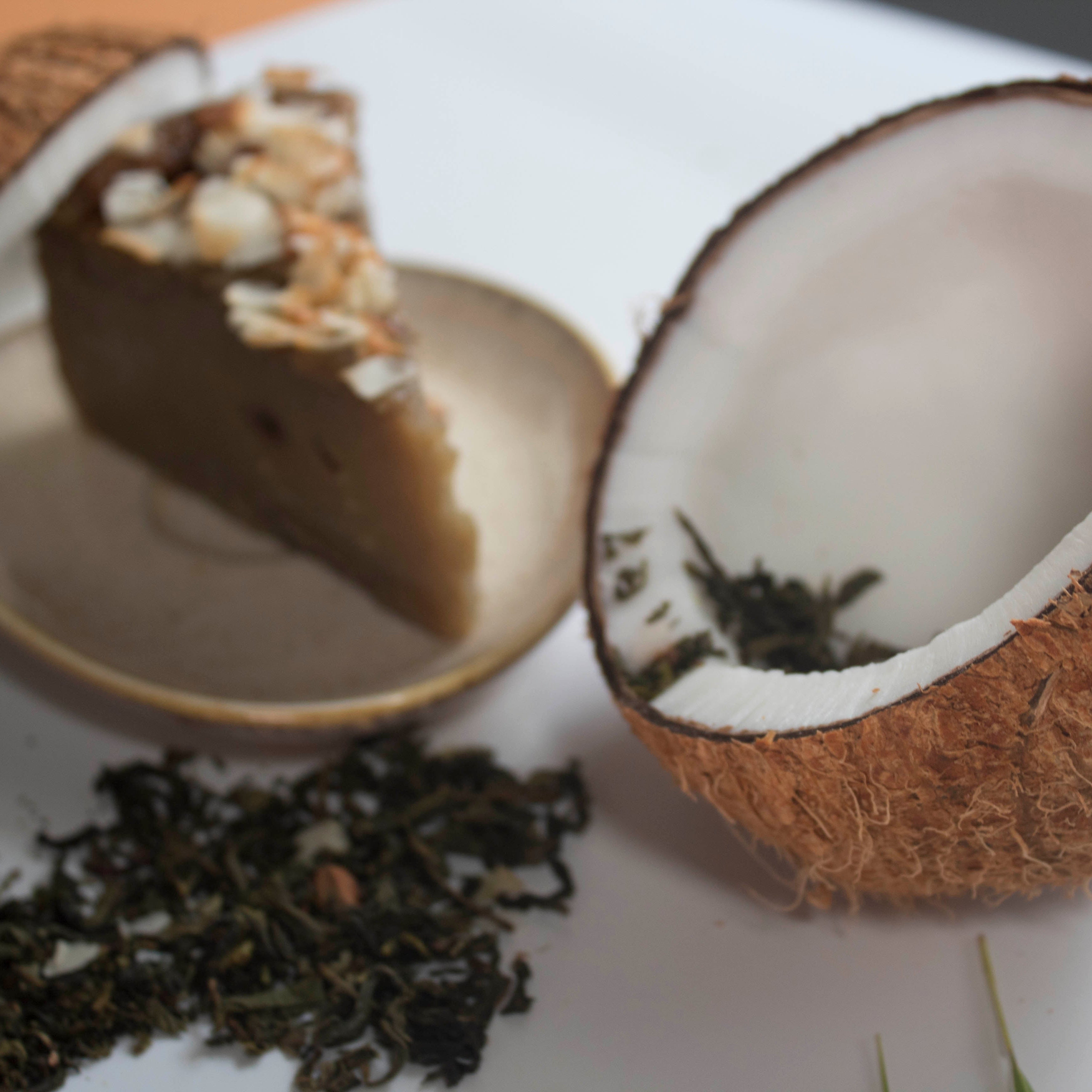 Coconut split open with a slice of cake and tea on a white surface